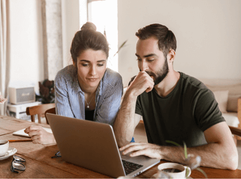 Couple consultant ensemble leur ordinateur à domicile, illustrant la gestion du prélèvement à la source des couples.