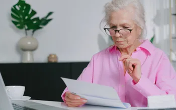 Retraitée consultant un document à son bureau, illustrant les démarches liées au cumul emploi-retraite