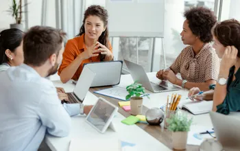 Réunion de travail entre collaborateurs autour d'un ordinateur portable, illustrant la gestion de la taxe d'apprentissage en entreprise.