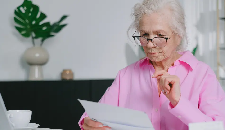 Retraitée consultant un document à son bureau, illustrant les démarches liées au cumul emploi-retraite