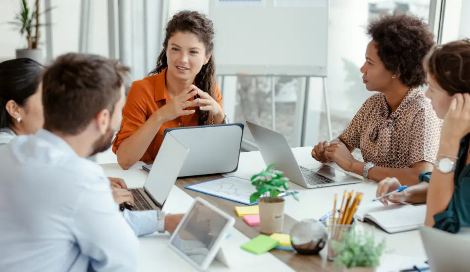 Réunion de travail entre collaborateurs autour d'un ordinateur portable, illustrant la gestion de la taxe d'apprentissage en entreprise.